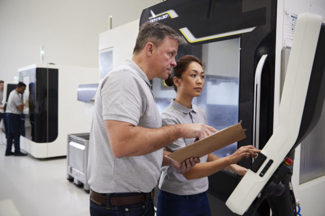 Engineer Training Female Apprentice To Use CNC Machine In Factory